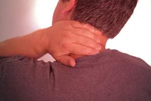 A person with neck pain holding his neck.