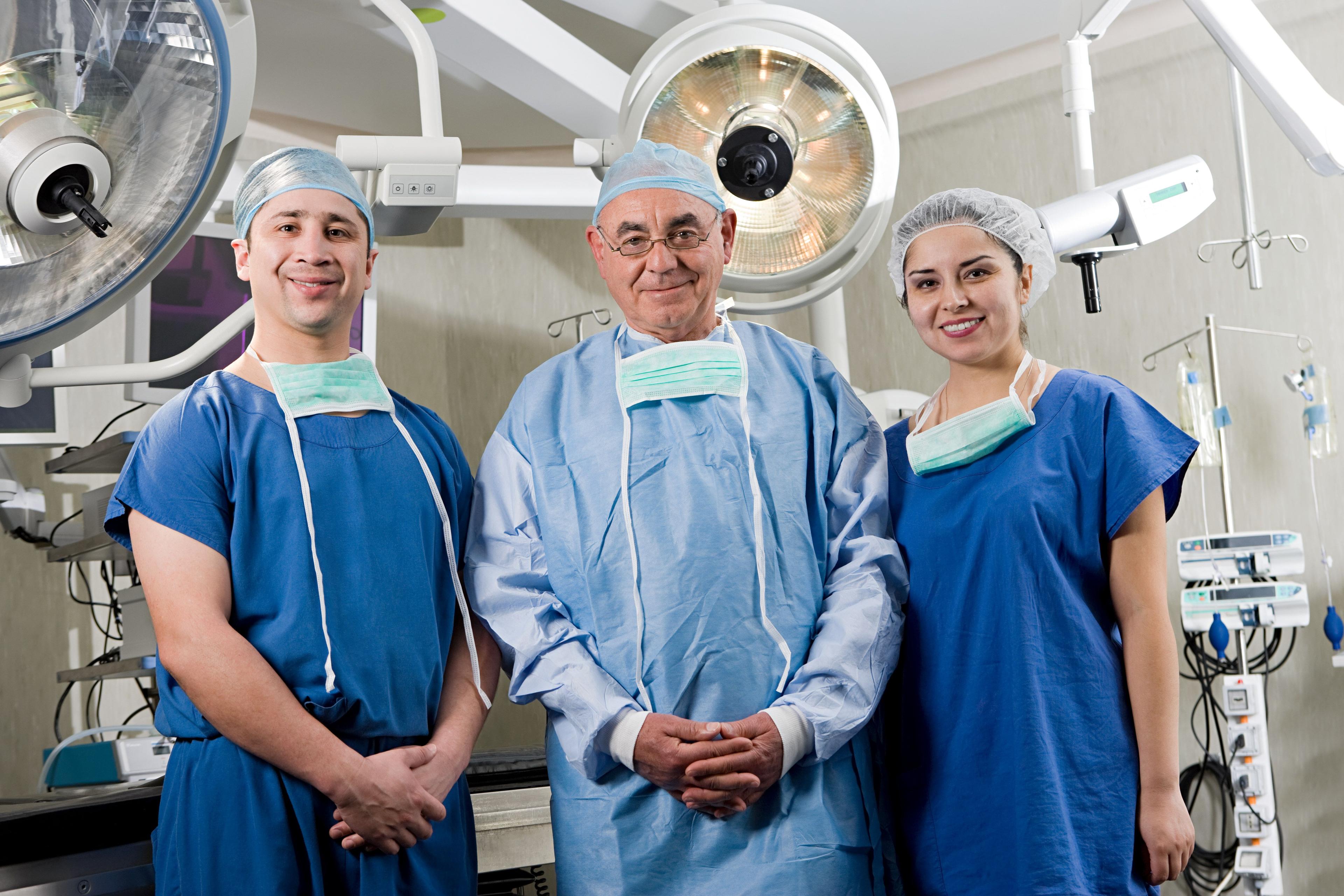 Three endoscopic spine surgeons in an operating room, posing for the camera.