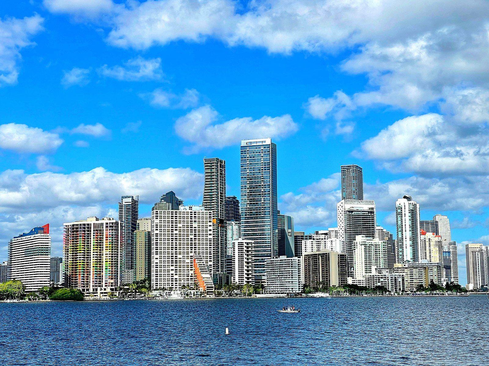 Miami skyline view from water, showing modern buildings under blue sky.