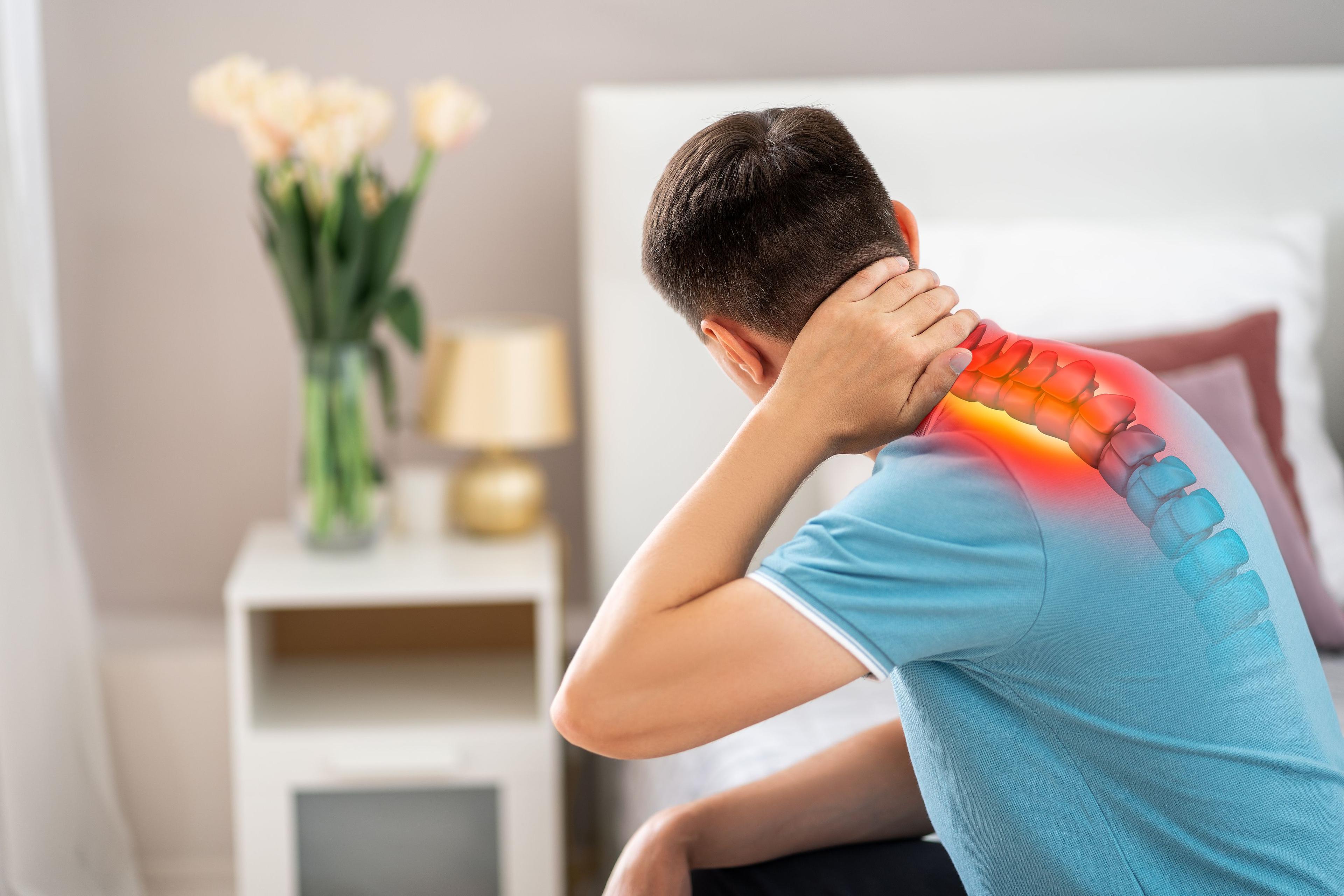 Man holding neck with pain radiating down the spine indicating a bulging disc.