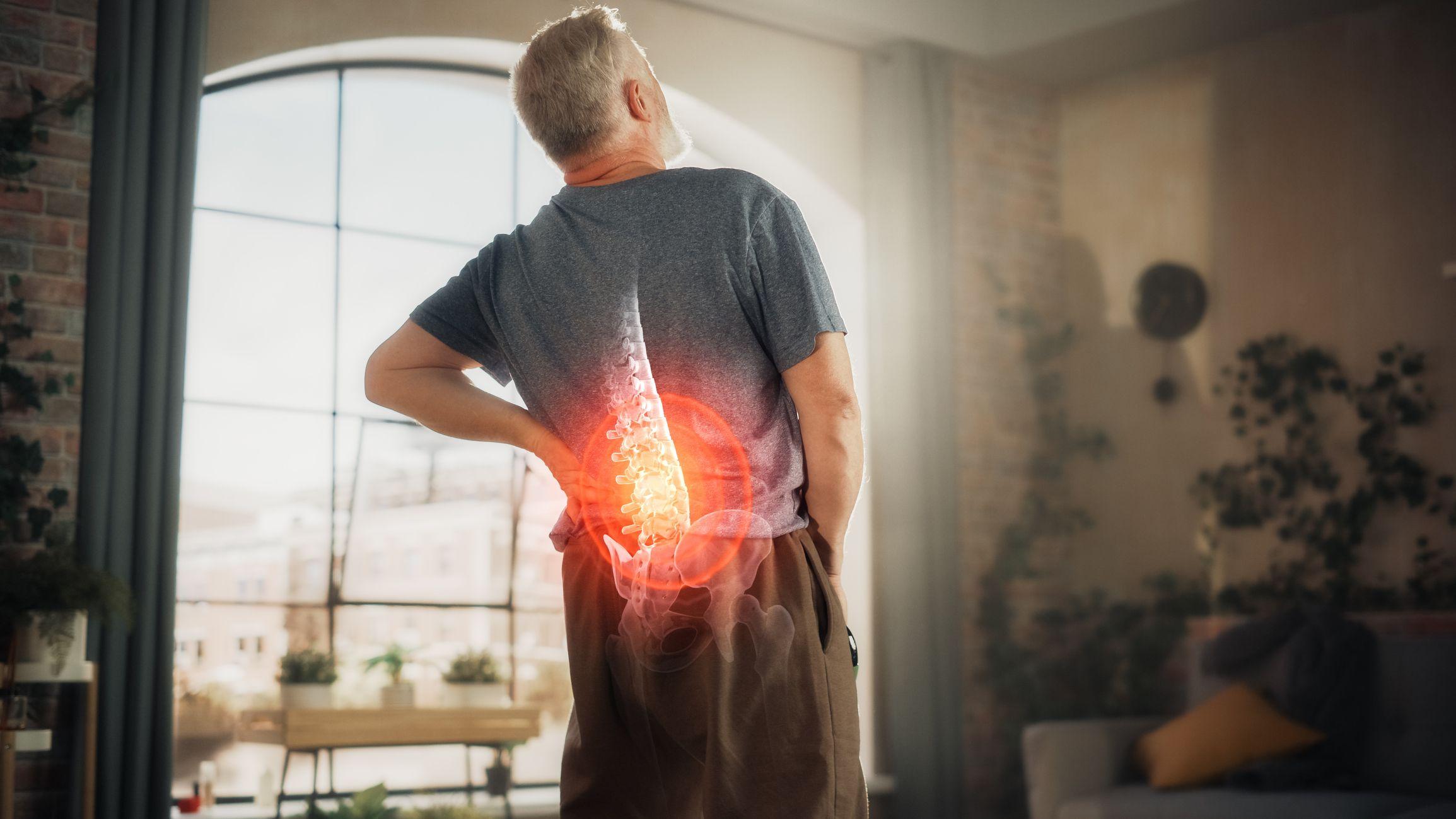 Man with a highlighted spine showing areas affected by spondylitis in a living room.
