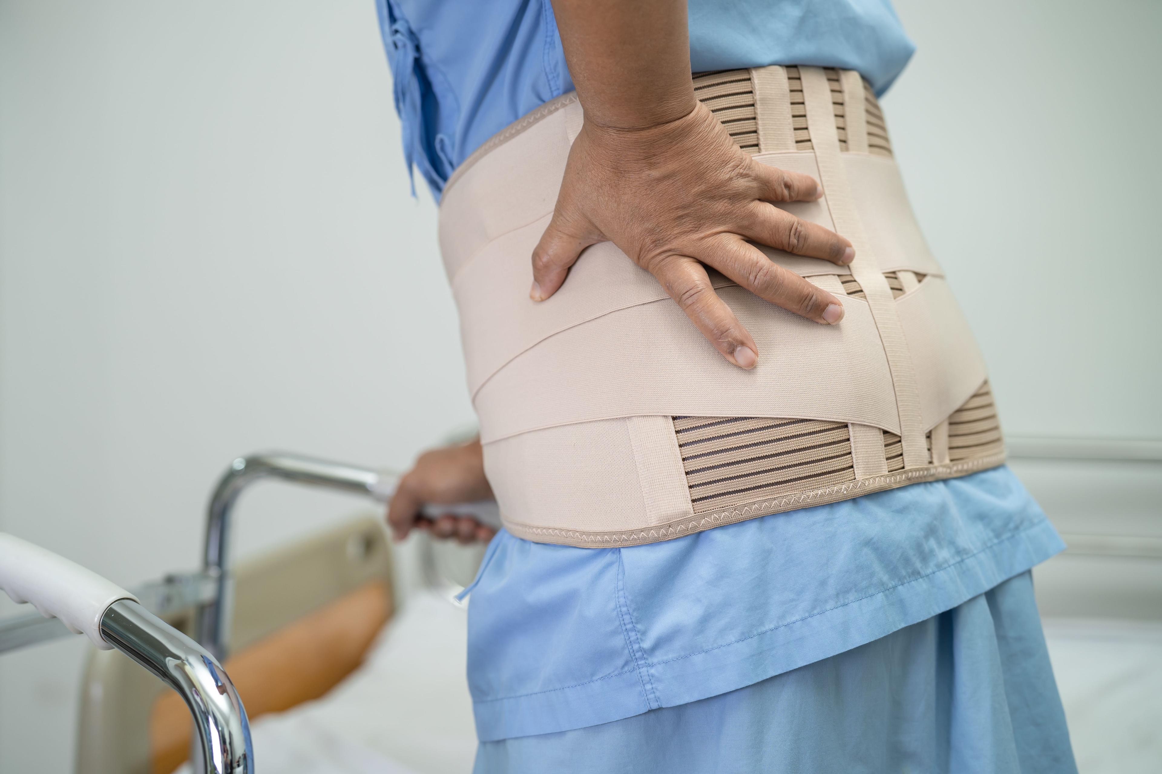 Person wearing a back brace, illustrating chronic pain