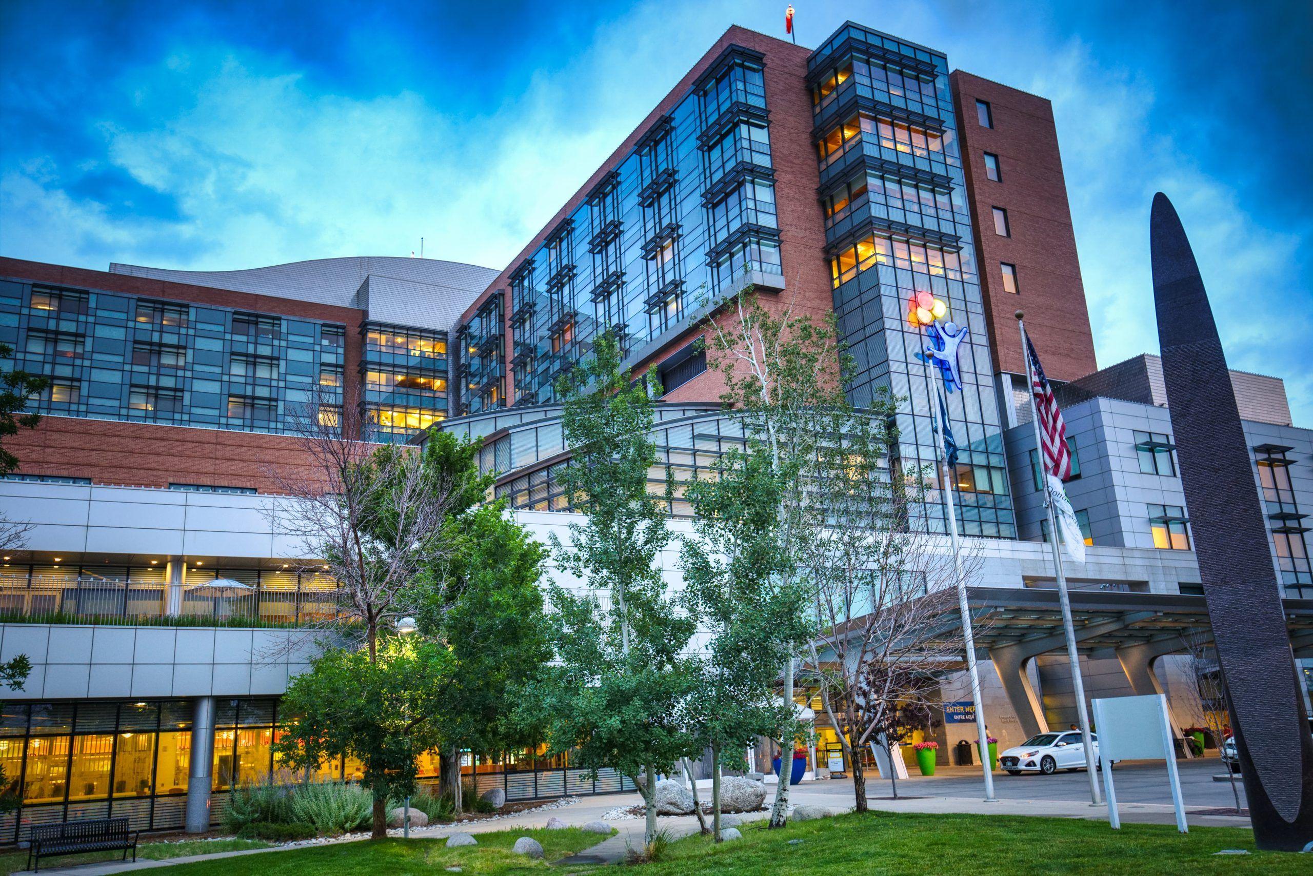 Modern hospital building with large glass windows and flags in front.