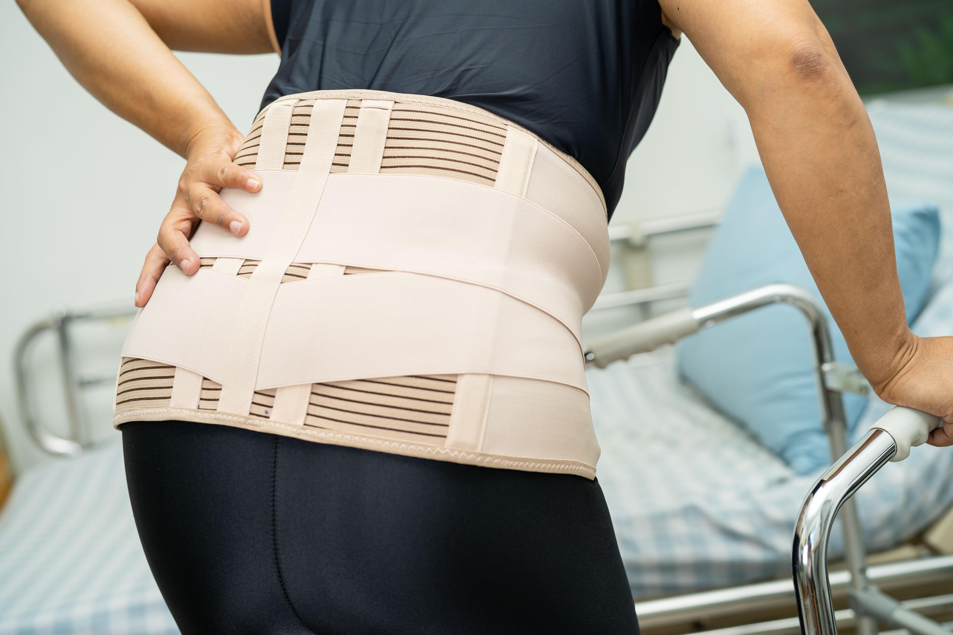 Women wearing back brace bending over in pain
