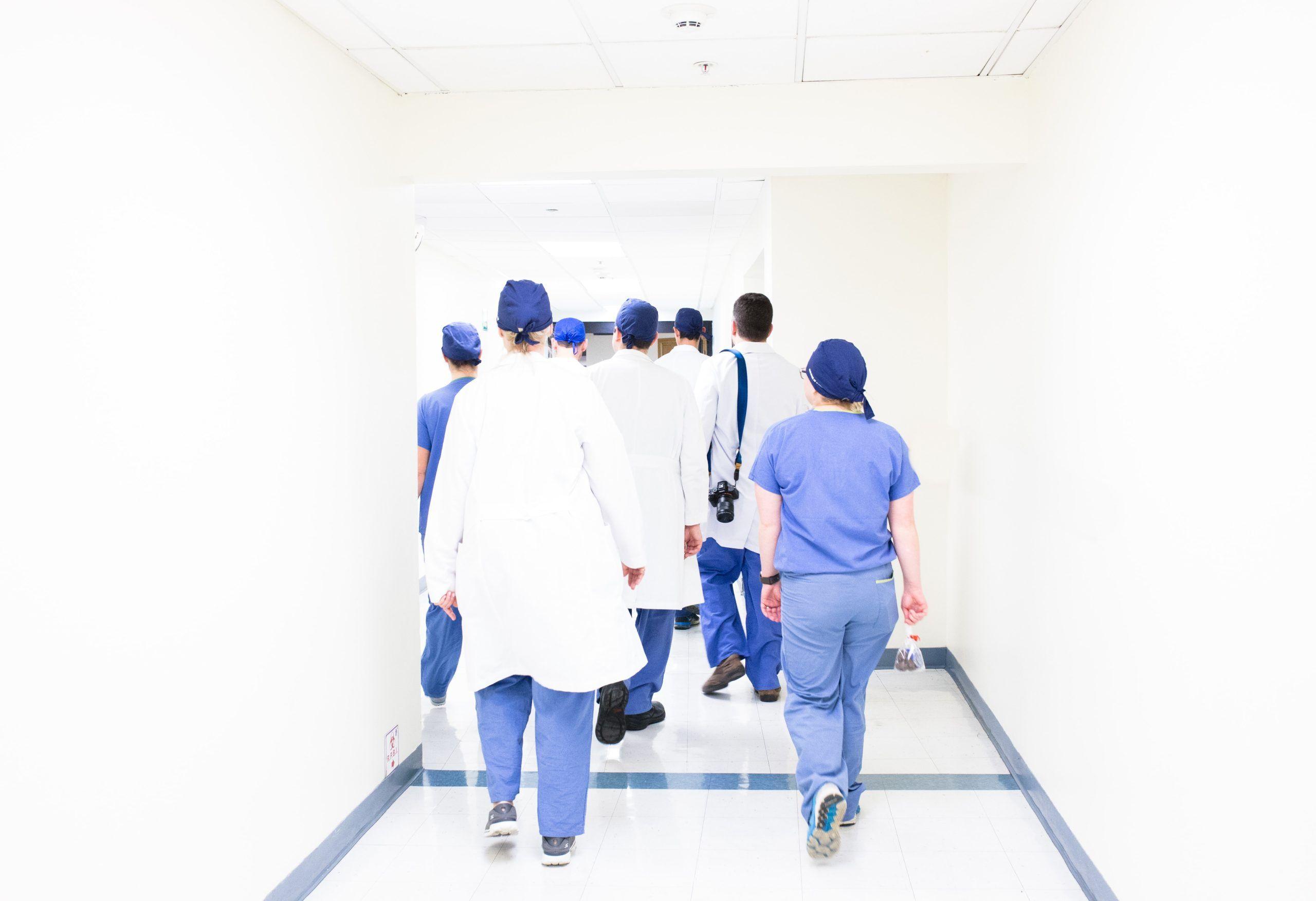 Group of medical staff in scrubs walking down a hospital corridor.