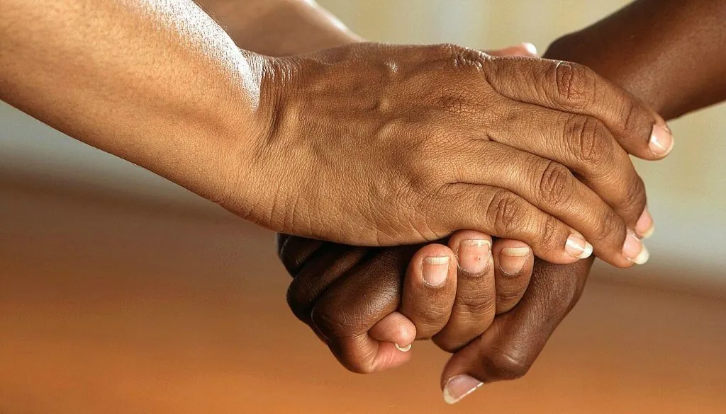 A picture of hands clasped together indicating care and support.