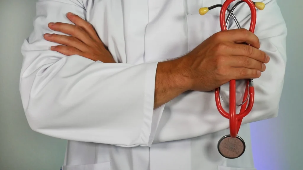 Doctor in white lab coat holding a red stethoscope.