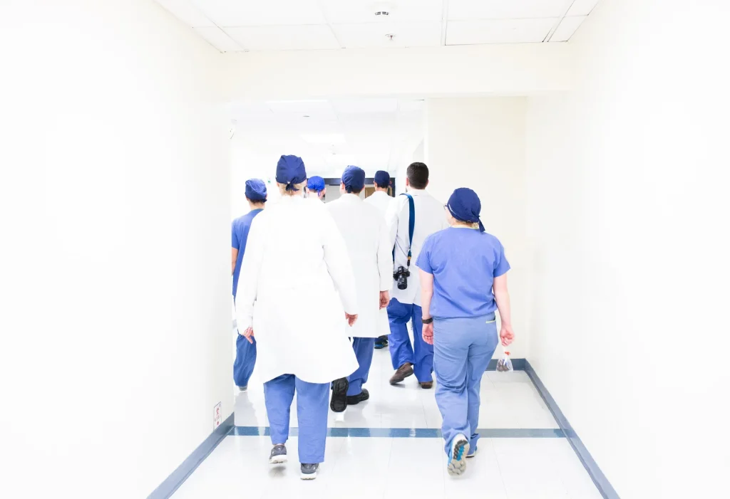 Group of medical staff in scrubs walking down a hospital corridor.