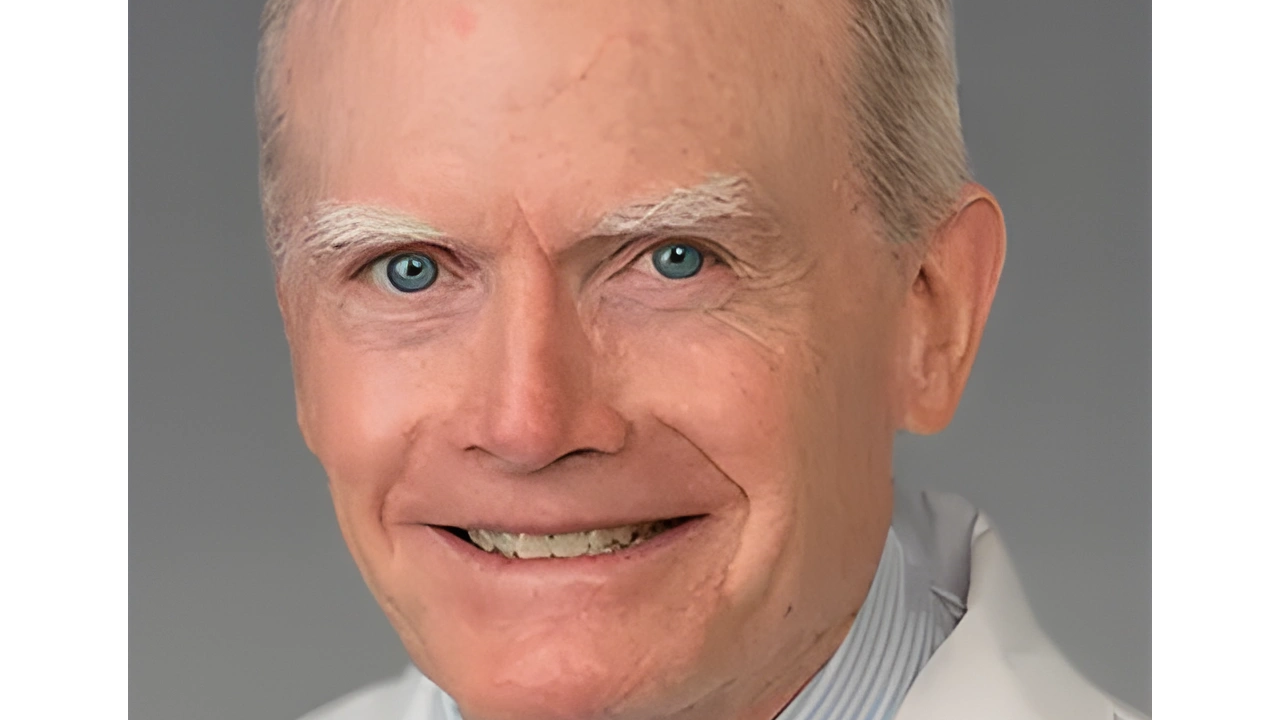 Smiling older man with gray hair and blue eyes in a white coat.