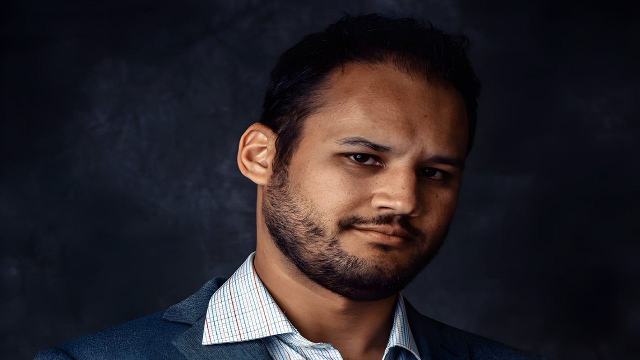 Man with a beard wearing a suit jacket and checkered shirt.