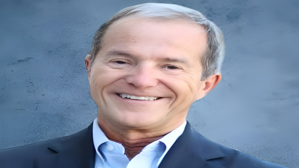 Smiling man in a suit against a textured blue background.