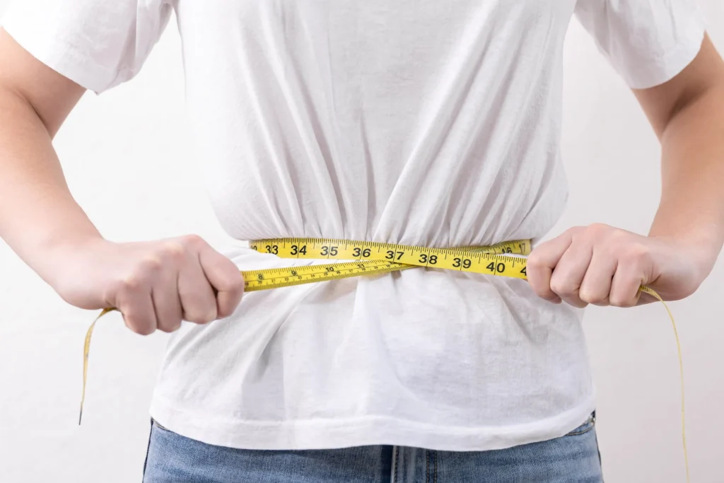 A person measuring their waist with a tape, related to herniated disc context.