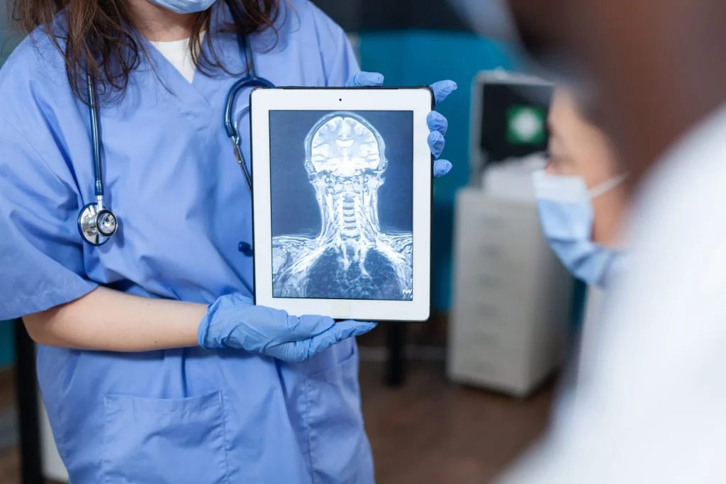 A healthcare professional displays a neck MRI scan on a tablet, illustrating neck pain issues.