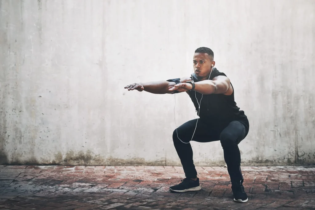 A man in athletic attire performs squats, demonstrating exercise posture important for herniated disc recovery.