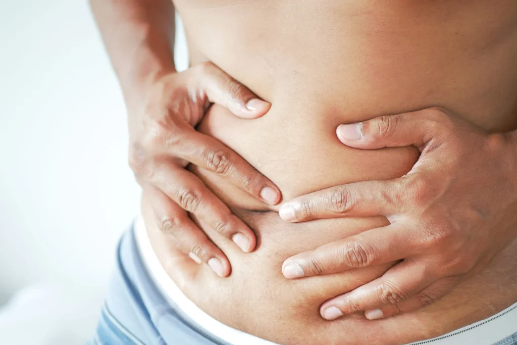 A person clutches their lower back in pain, indicating a herniated disc.