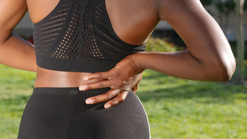 Woman clutching her lower back, possibly needing spine health treatment.