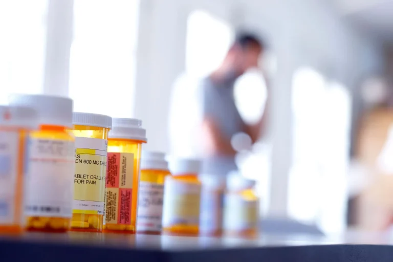 Prescription bottles lined up with a blurred person in the background.