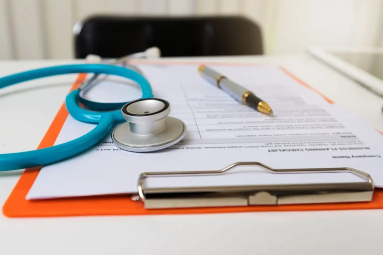 A stethoscope and pen resting on a clipboard with a document.