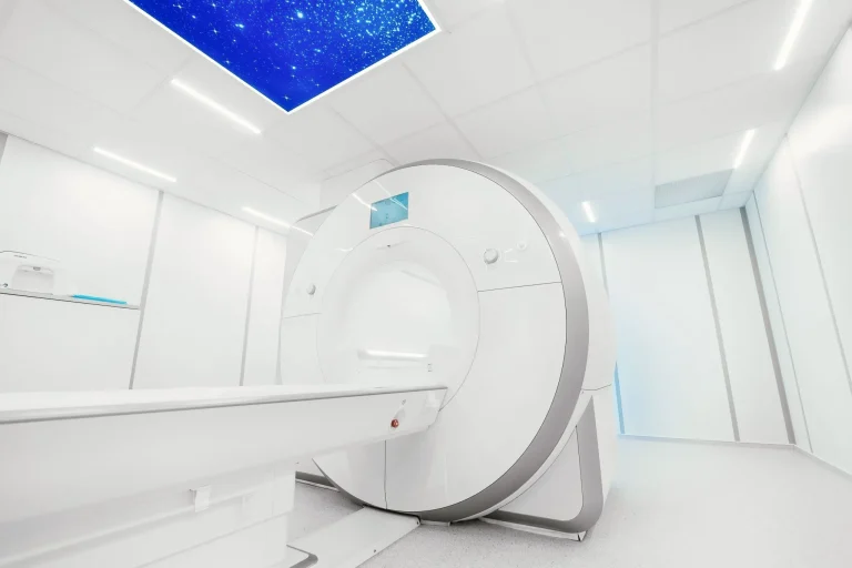 Modern MRI machine in a bright, clean medical room with a starry sky ceiling panel.