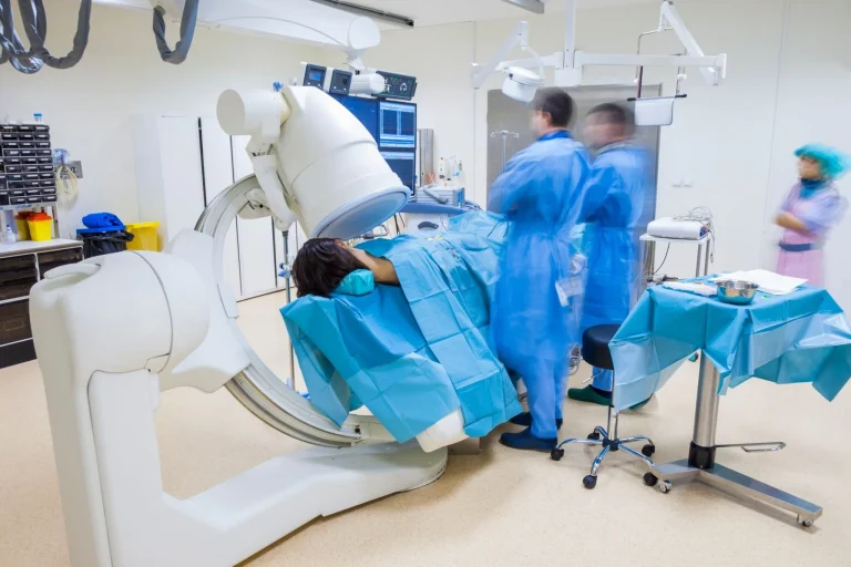 Medical team in a surgical room with a patient under an imaging machine.