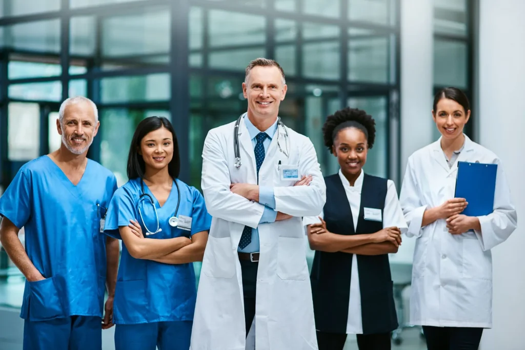 A diverse group of healthcare professionals stands confidently in a hospital setting.