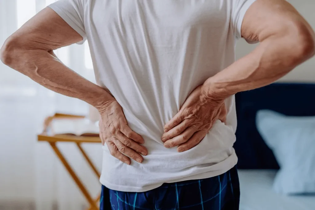 Person holding their lower back with both hands, suggesting discomfort.