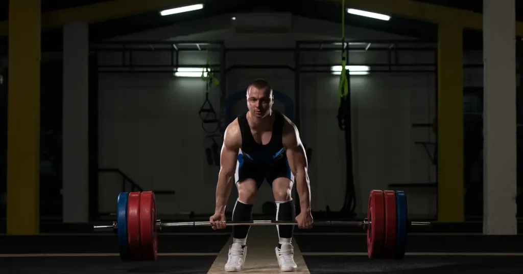 A weightlifter is preparing to lift a heavy barbell in a gym.