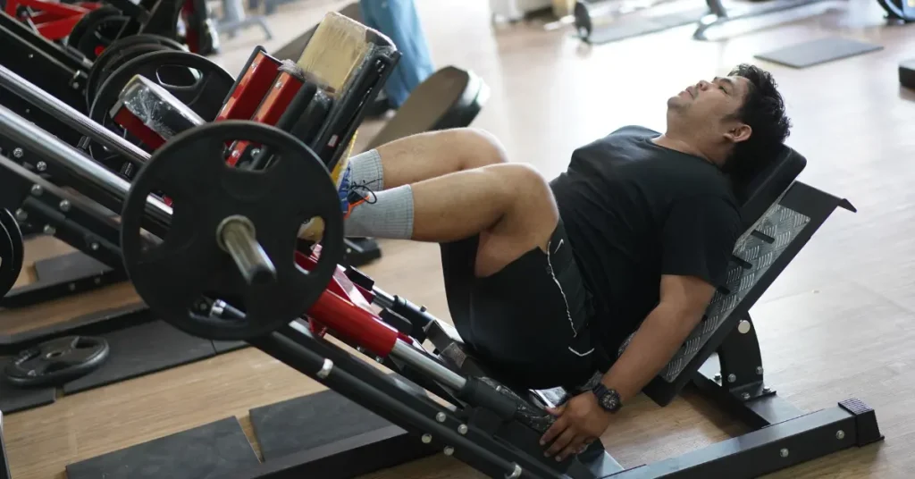 Man performing a leg press exercise on a machine at the gym, strengthening quadriceps, hamstrings, and glutes.