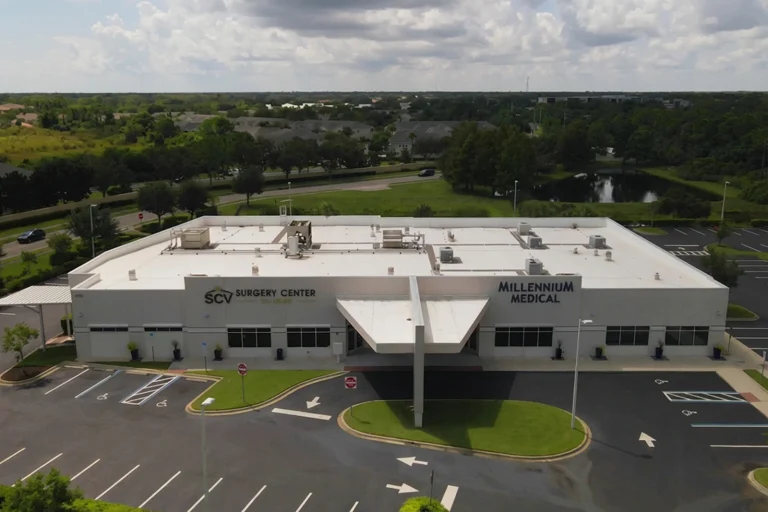 Aerial view of a white building labeled "SCV Surgery Center" and "Millennium Medical," surrounded by greenery and a parking lot.