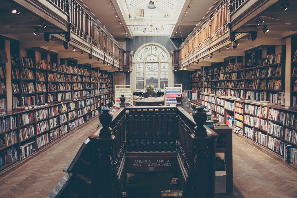 Elegant library interior with wooden railings, bookshelves, and a large arched window.
