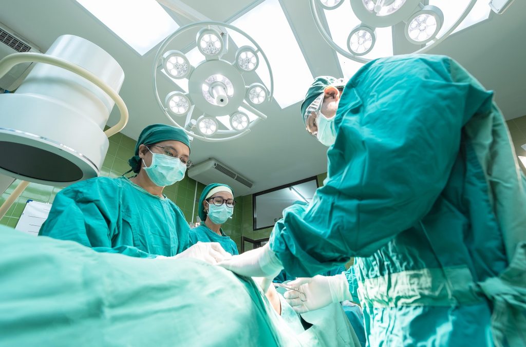 Surgeons in an operating room performing a procedure under bright lights.