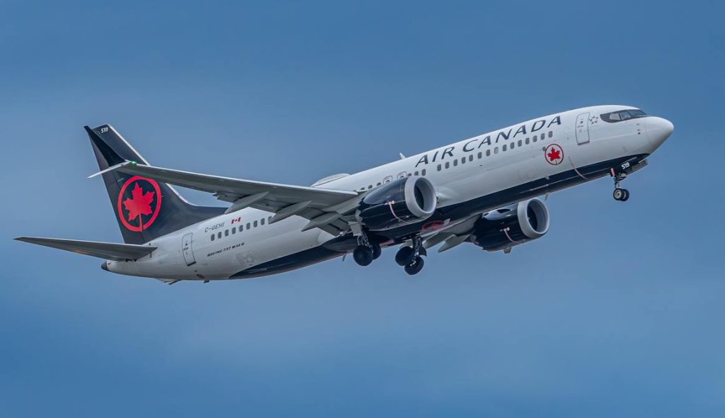 Air Canada airplane flying against a cloudy sky.