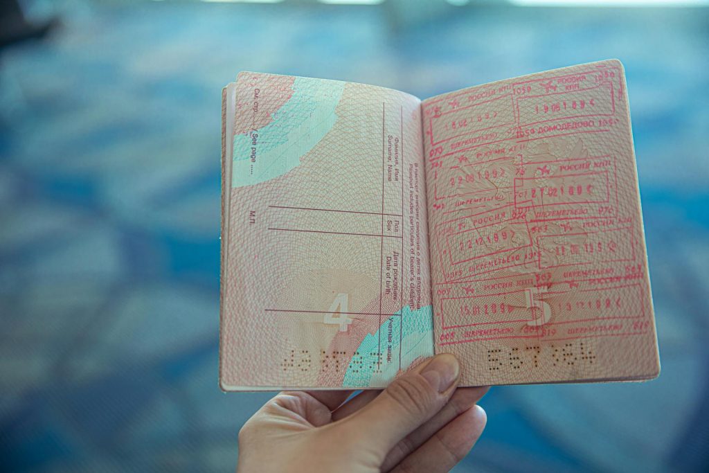 Open passport showing visa stamps held by a hand.