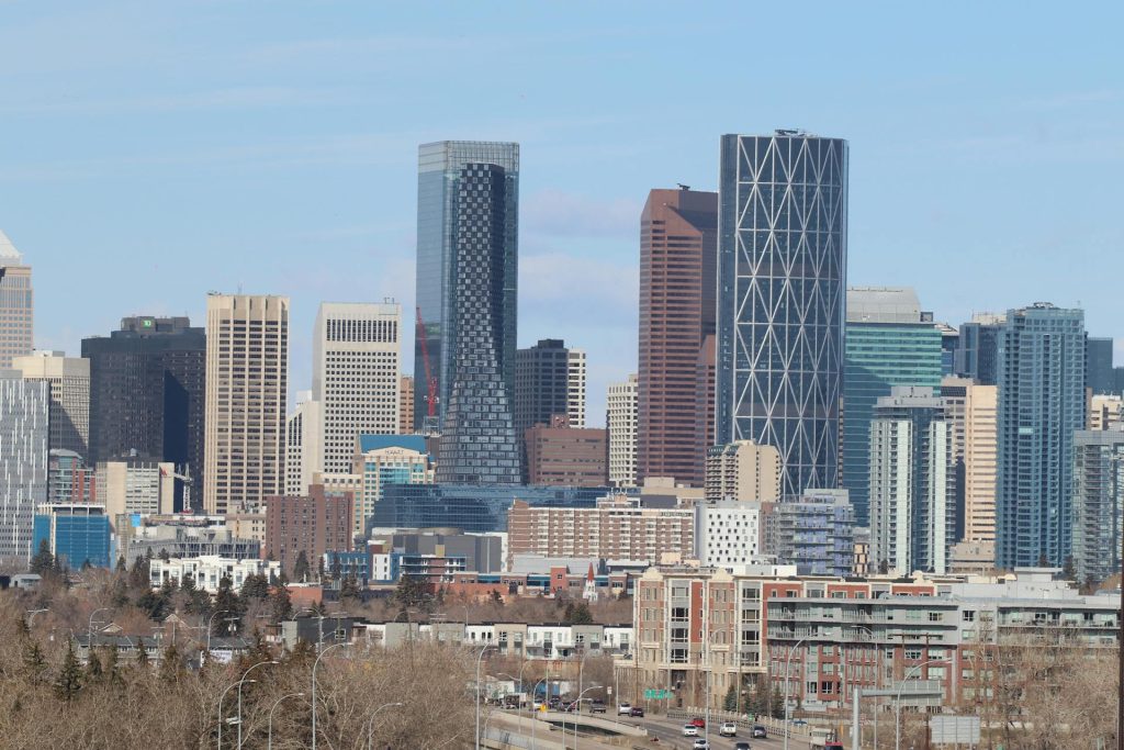Calgary skyline with various modern skyscrapers under a clear blue sky.
