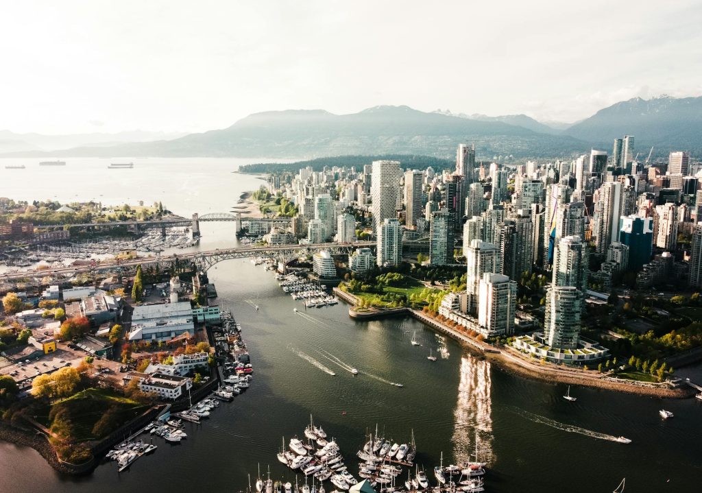 Aerial view of a city skyline with tall buildings, bridges, and boats in a harbor.