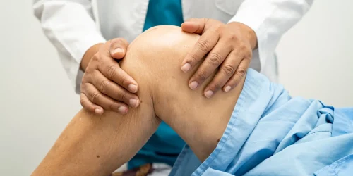 A doctor examines a patient's knee, potentially related to herniated disc symptoms.