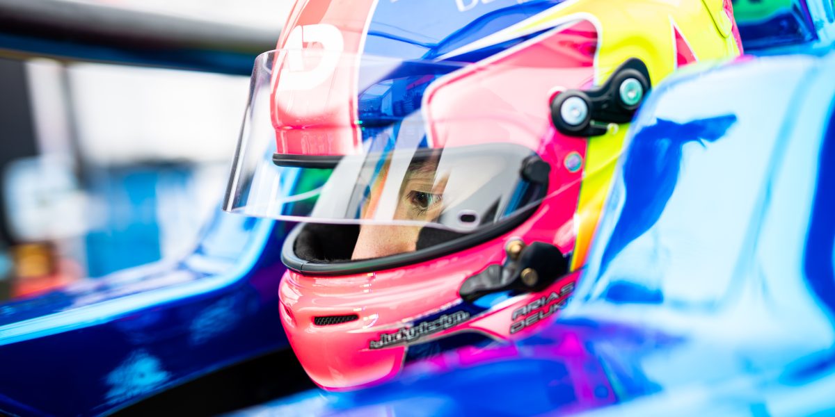 Race car driver focused inside a colorful helmet.