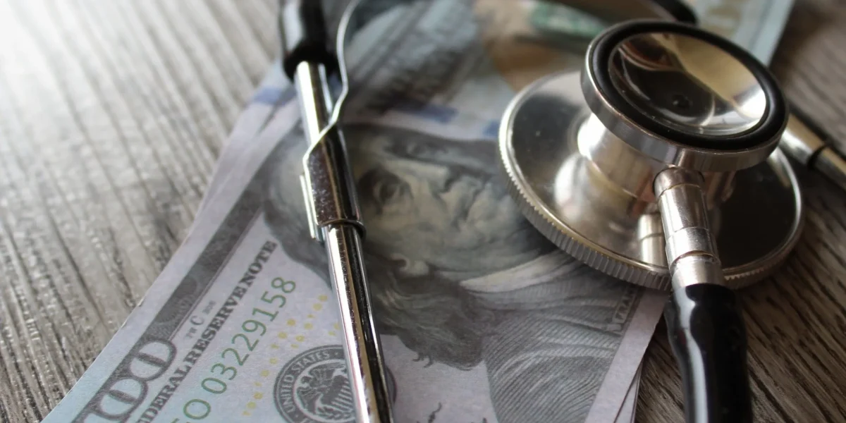 Hundred dollar bills and stethoscope depicting the high cost of spinal fusion surgery