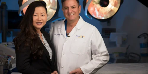Two medical professionals smiling in an operating room setting.