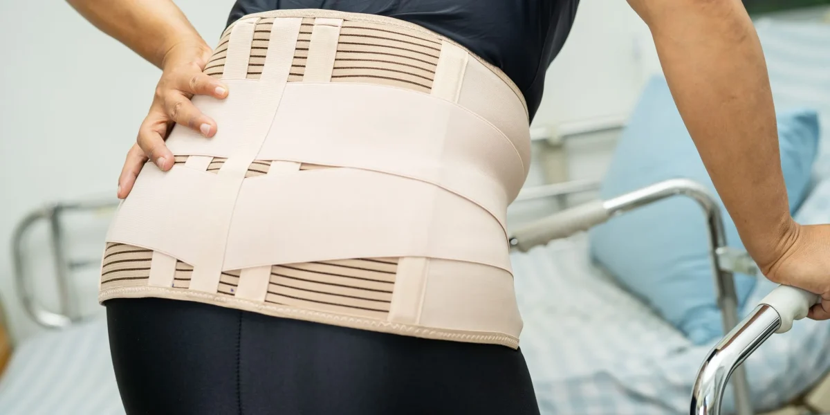 Women wearing back brace bending over in pain