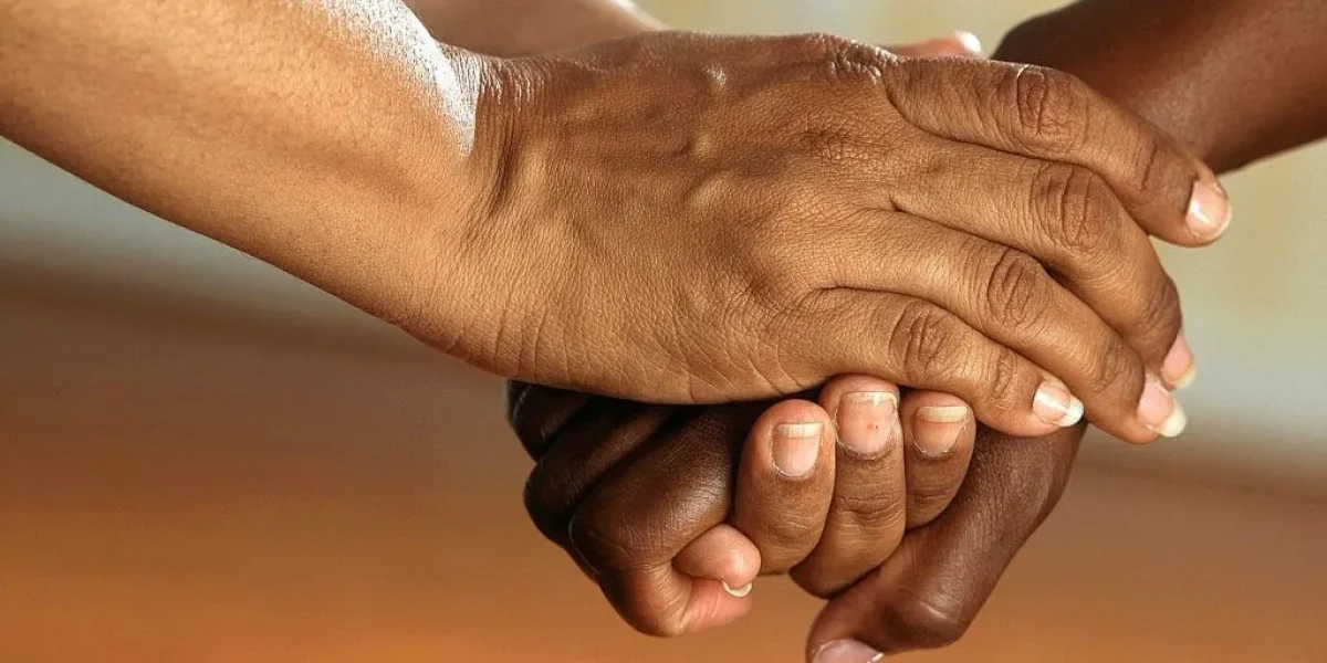 A picture of hands clasped together indicating care and support.
