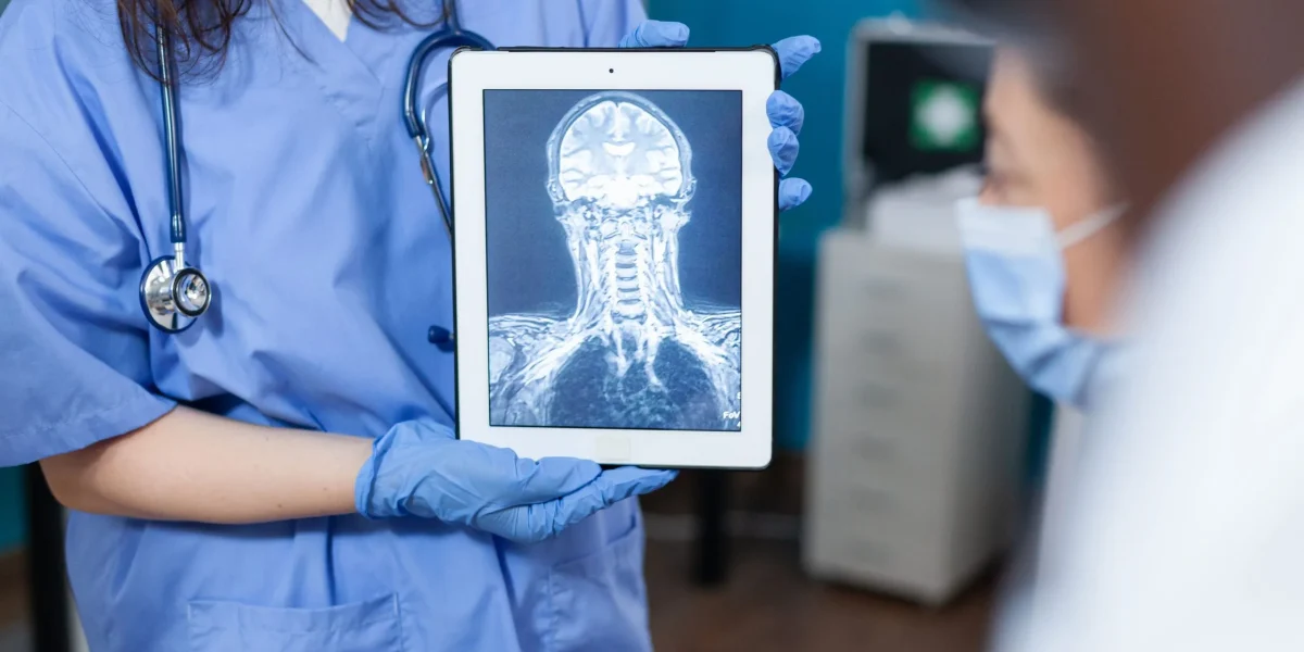 A healthcare professional displays a neck MRI scan on a tablet, illustrating neck pain issues.