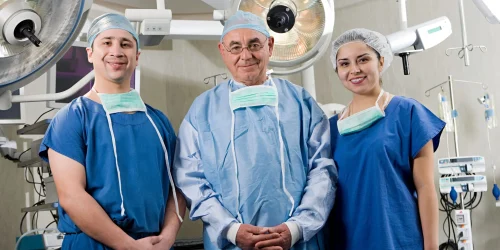 Three endoscopic spine surgeons in an operating room, posing for the camera.
