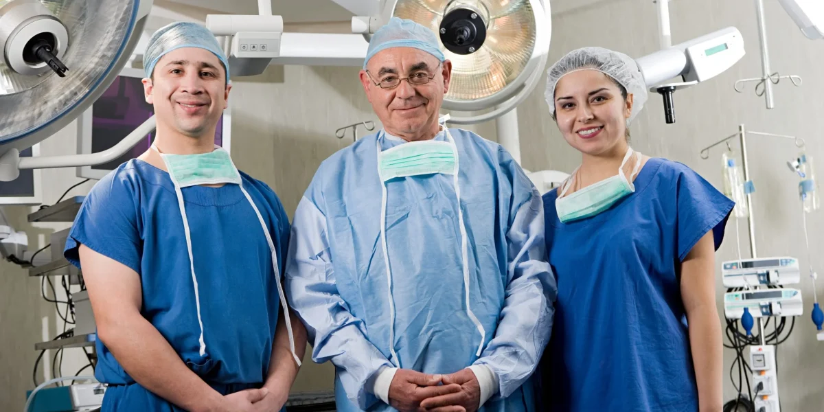 Three endoscopic spine surgeons in an operating room, posing for the camera.