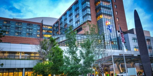 Modern hospital building with large glass windows and flags in front.